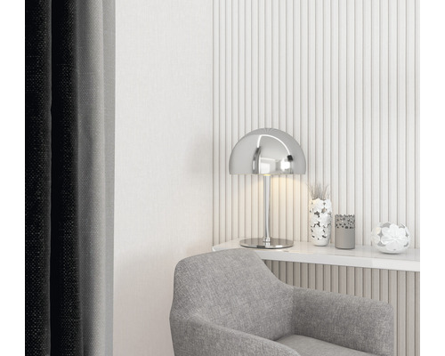 Dekoratives Wohnzimmer mit grauem Sessel, silberner Lampe und floralen Akzenten