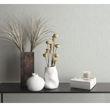 Dekorative Vasen mit Pflanzen und Kerze auf einem Regal