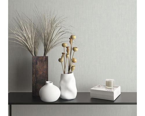 Dekorative Vasen mit Pflanzen und Kerze auf einem Regal