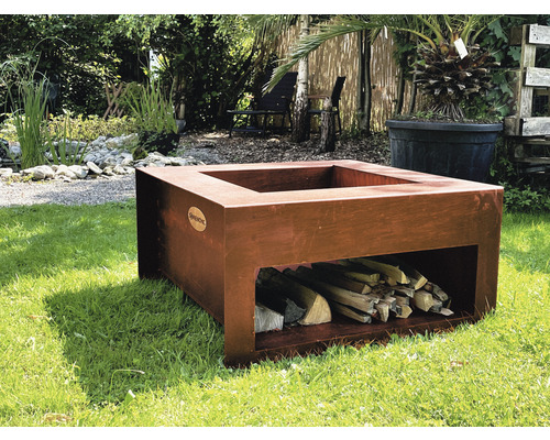 Quadratische Feuerstelle aus Metall mit Holzscheitlager im Garten