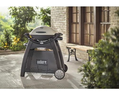 Barbecue à gaz Weber Q 1200 sur une terrasse devant une maison.