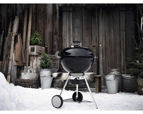 Kugelgrill im Schnee vor einer Holzhütte