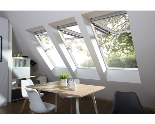Innenansicht eines Dachgeschosses mit drei Dachfenstern über einem Esstisch.
