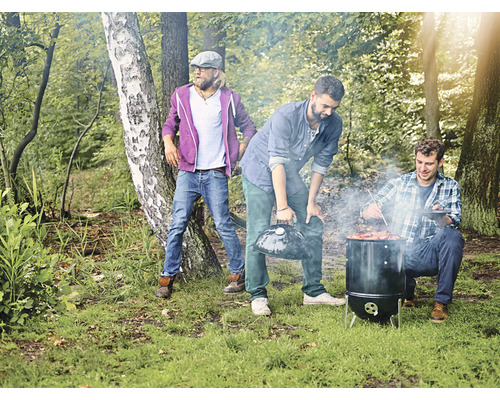 Grillszene im Freien mit drei Männern beim Grillen im Wald.