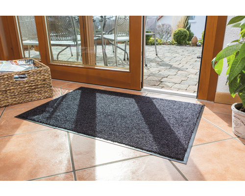 Paillasson gris devant une porte de terrasse sur un sol carrelé
