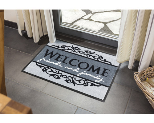 Fussmatte mit der Aufschrift Willkommen für Freunde und Familie vor einer Tür