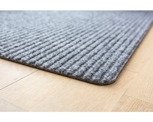 Graue Fussmatte mit gerippter Oberfläche auf Holzboden