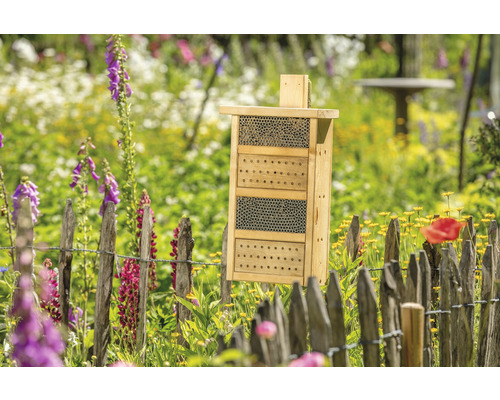 Hôtel à insectes en bois dans un jardin fleuri
