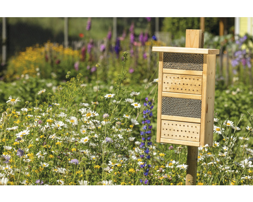 Hôtel à insectes en bois dans un jardin fleuri