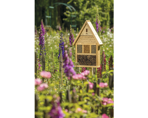 Insektenhotel aus Holz im Garten mit Blumen