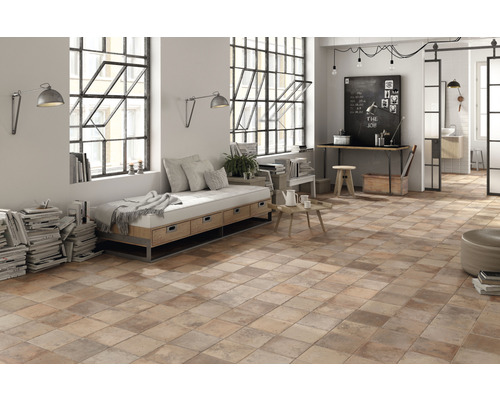 Pièce lumineuse avec carrelage au sol de style terre cuite, coin salon et espace de travail.