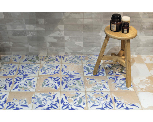 Aménagement de salle de bains avec des carreaux imitation pierre au mur et des carreaux à motifs sur le sol, ainsi qu''un tabouret avec décoration