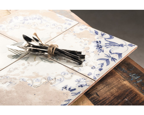 Carreaux de céramique décoratifs avec motif floral et un ensemble de couverts, liés avec une ficelle.