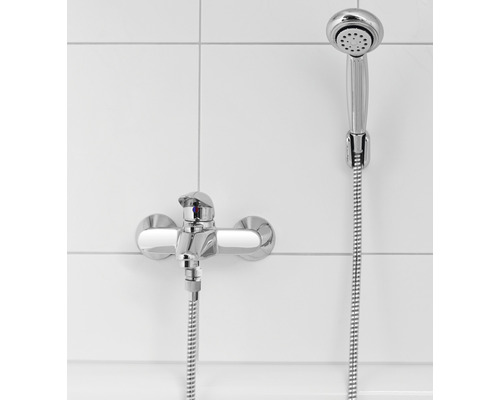 Brausegarnitur mit Wandarmatur vor weissem Fliesenhintergrund