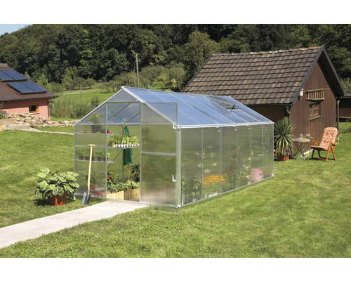 Serre sur une pelouse avec des plantes à l''intérieur.