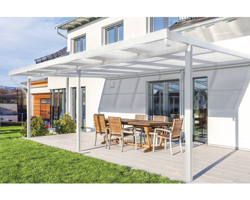 Toiture de terrasse gutta Premium polycarbonate opale 611 x 306 cm blanc Terrasse avec toit de terrasse, table et chaises devant une maison.