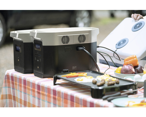 Deux centrales électriques portables EcoFlow sur une table avec des aliments préparés sur un gril