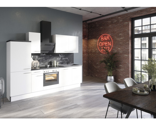 Cuisine moderne avec façades blanches, hotte aspirante et table à manger dans un espace de type loft avec un mur en briques.