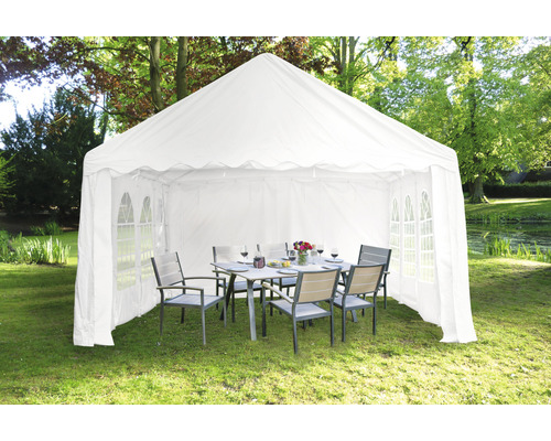 Weisses Partyzelt mit Tisch und Stühlen im Garten.