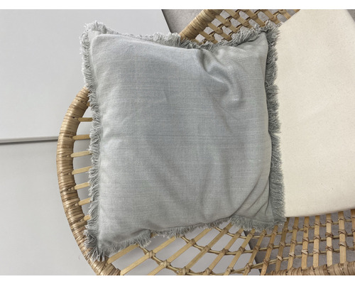 Coussin carré avec des franges sur un fauteuil en rotin