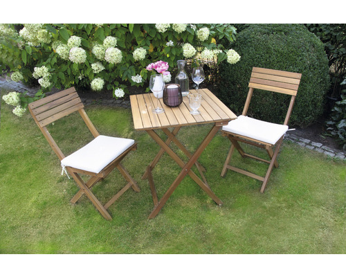 Scène de jardin avec table en bois et deux chaises en bois avec coussins d''assise sur une pelouse