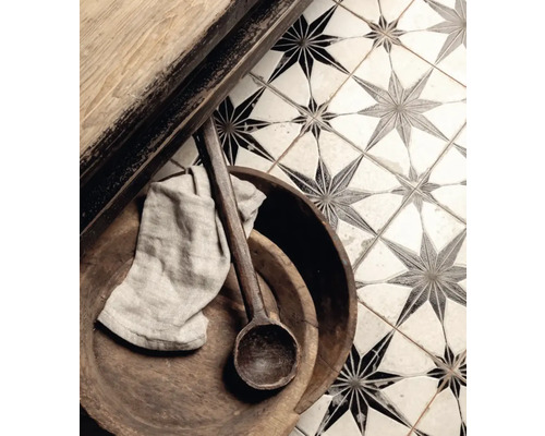 Detailaufnahme von Bodenfliesen mit Sternmuster, kombiniert mit Holzelementen, einem Holzlöffel und einem Tuch.