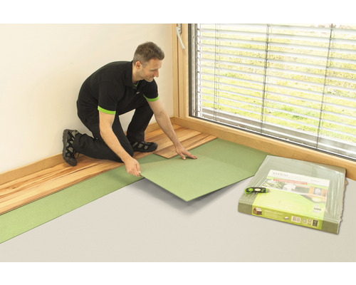 Ein Mann verlegt Trittschalldämmung und Laminat in einem Raum.