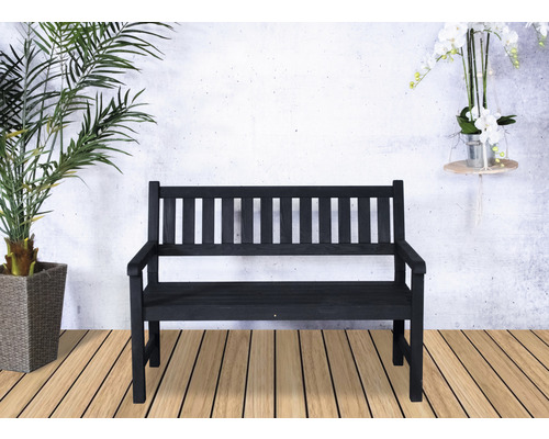Banc de jardin en bois avec accoudoirs devant un mur blanc