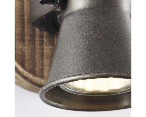 Nahaufnahme einer Wandleuchte mit Holzsockel und Metallkopf