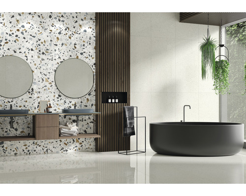 Salle de bains lumineuse avec lavabo, miroirs, baignoire et carrelage aspect terrazzo