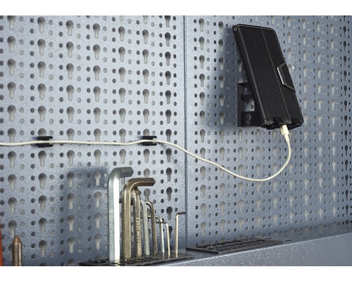 Panneau perforé avec outils, tablette et câble de chargement.
