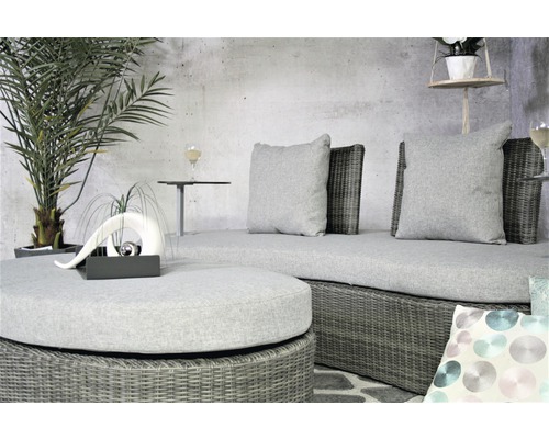 Szene mit Rattansitzgruppe, bestehend aus Sofa, Hocker und Kissen auf Terrasse.