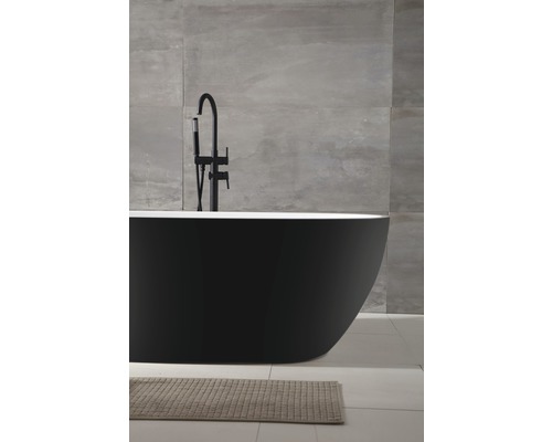 Baignoire îlot noire avec robinetterie et tapis de bain dans une salle de bains avec mur carrelé