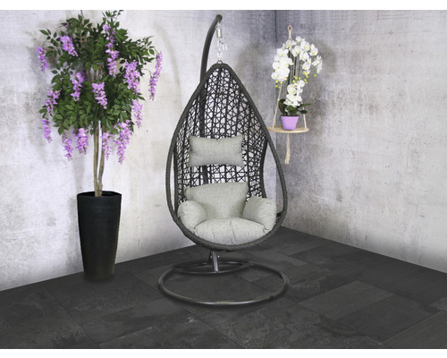 Mise en scène avec un fauteuil suspendu en forme de panier avec coussins, une glycine en pot et une orchidée suspendue