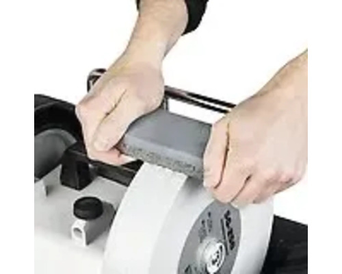 Personne affûtant un outil avec une meule