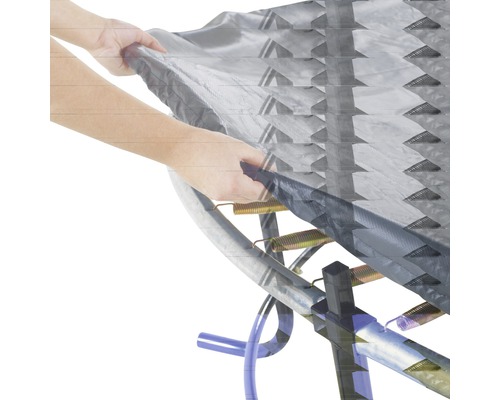 Gros plan d''un trampoline avec des ressorts et une couverture maintenue par une main.