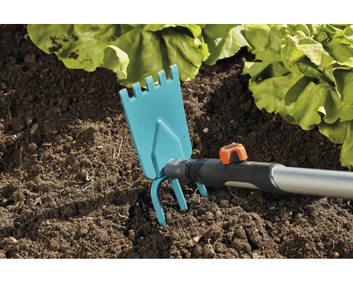 Gartenhacke im Einsatz in der Erde neben Salatpflanzen.