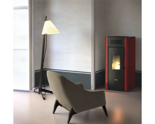 Wohnzimmer mit Sessel, Stehlampe und rotem Pelletofen