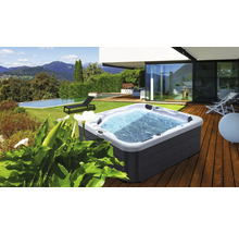 Whirlpool auf einer Holzterrasse mit Garten und Pool im Hintergrund