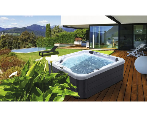 Whirlpool auf einer Holzterrasse mit Garten und Pool im Hintergrund
