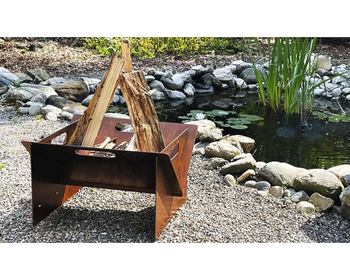 Feuerstelle aus Metall mit Brennholz neben einem Teich