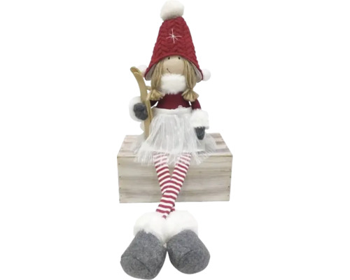 Dekorative Stoffpuppe mit Skiern auf einer Holzkiste