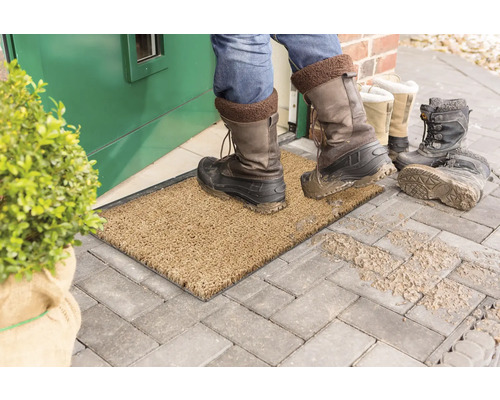 Schmutzfangmatte vor einer Haustür mit schmutzigen Stiefeln