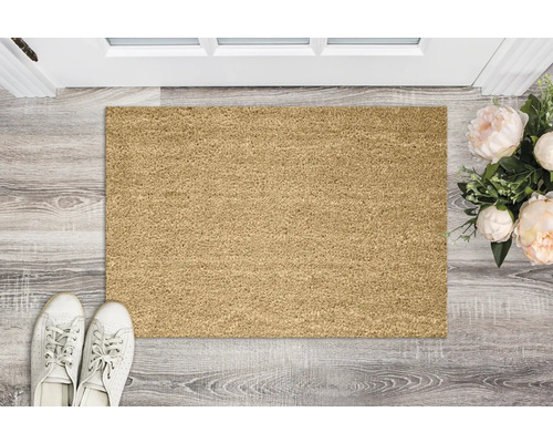 Rechteckige Fussmatte aus Naturfasern vor einer Tür mit Schuhen und Blumen