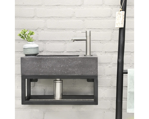 Lavabo avec robinet, meuble sous-lavabo et porte-serviettes devant un mur de briques