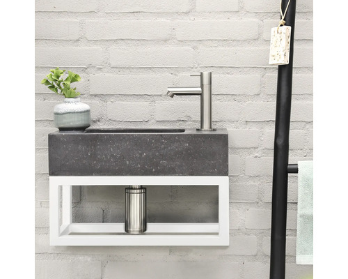 Waschbecken mit Armatur, Pflanze und Handtuchhalter vor einer Ziegelwand