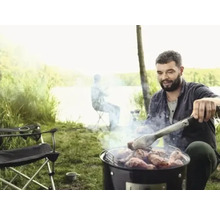 Mann grilliert Fleisch im Freien mit Grillzange
