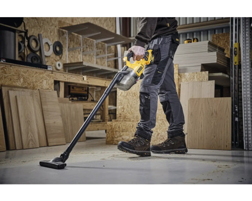 Un ouvrier utilise un aspirateur sans fil DeWalt dans un atelier.