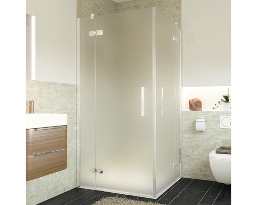 Douche d''angle en verre dépoli dans une salle de bain avec lavabo et toilettes.