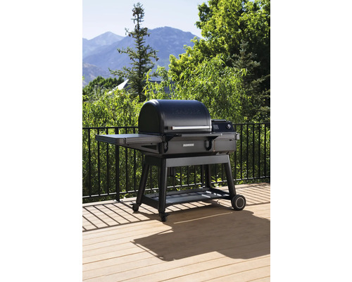 Grill Traeger sur une terrasse avec rambarde et montagnes en arrière-plan.